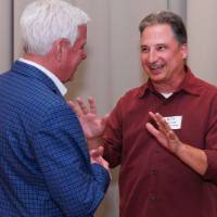 An alum smiles and laughs speaking to Troy Farley